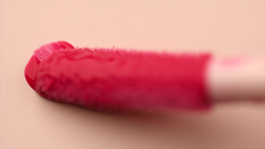 Lipgloss make-up smudge, smear. Cosmetic liquid lip gloss, lipstick pink color smudge, smear, stroke. Lip gloss Make up smears on beige background. Brush, applicator. Smooth Texture Royalty-Free Stock Footage #1096329055