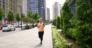 4K video footage of a woman running or jogging, a front view of a girl in town. A girl in sportswear is doing outdoor fitness activities. Concepts of healthy lifestyle and sports