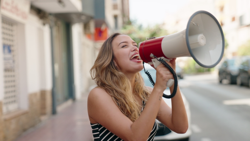 Young beautiful hispanic woman using megaphone screaming at street Royalty-Free Stock Footage #1096330819