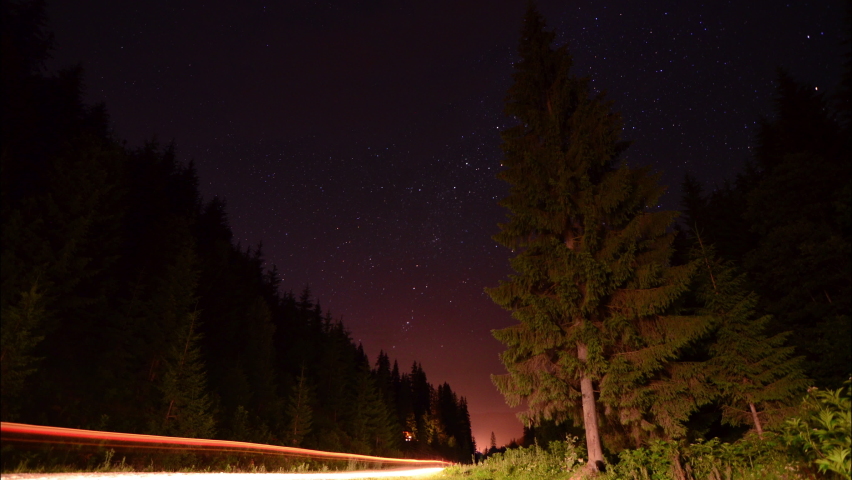4k Timelapse of moving star trails in night deep forest sky. The Milky Way galaxy rotating over the mountain range in summer time
