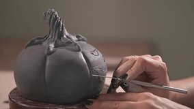 girl potter makes a pumpkin from a piece of clay for Halloween. live video