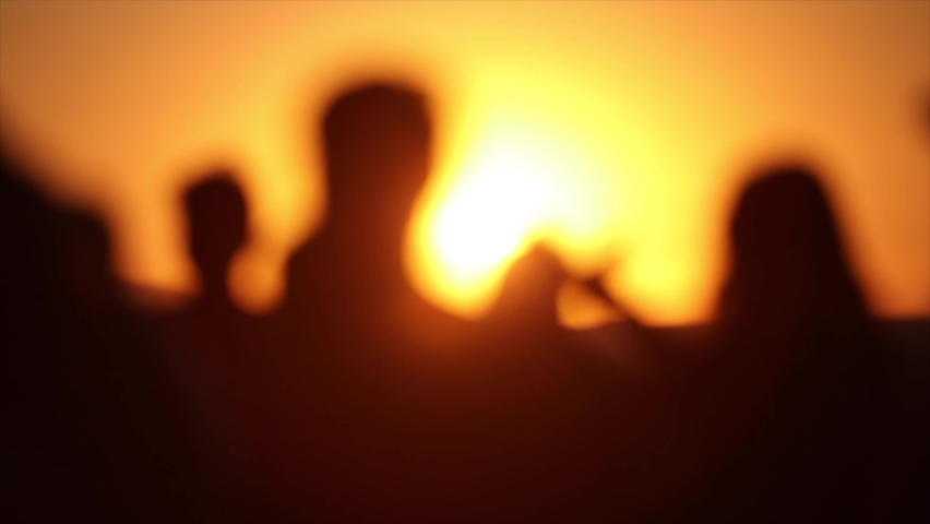 People are dancing on the beach during the sunset.