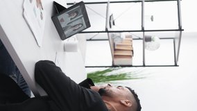 Vertical video. Boring lesson. Sleeping man. Virtual connection. Exhausted guy yawning laying head on hands having online meeting on tablet computer light room interior.