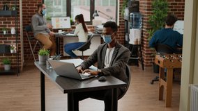 African american businessman working on laptop at office desk, using research data online to plan startup presentation. Employee sending professional email during covid 19 pandemic. - Powered by Shutterstock - Get 15% off with code: PIKWIZARD15