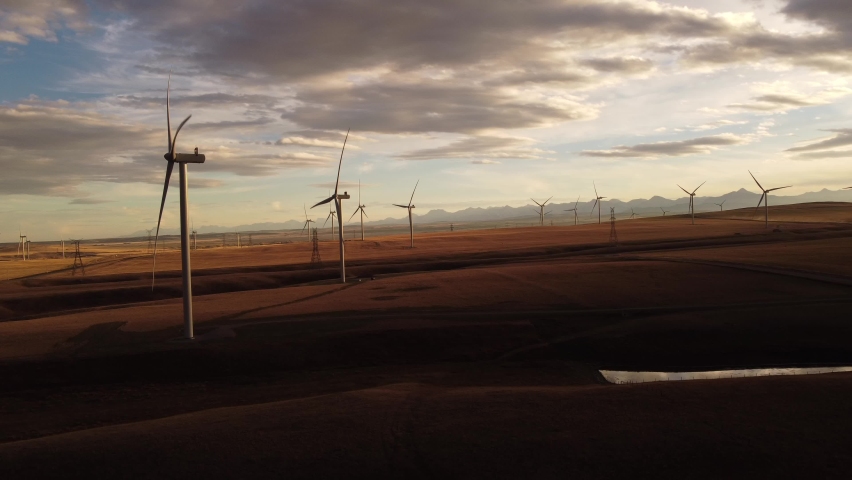 Aerial Wind Turbine Cinematic View of Windmills producing renewable energy on Alberta Farmlands during sunset. Royalty-Free Stock Footage #1096342731
