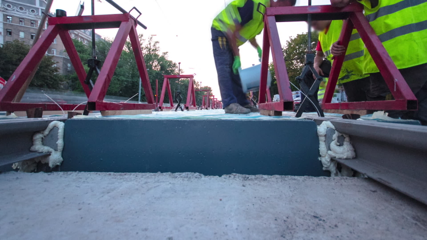 Tram rails at the stage of their installation and integration into concrete plates on the road timelapse hyperlapse. Filling by liquid resin for reduction of vibration and noice. The process of