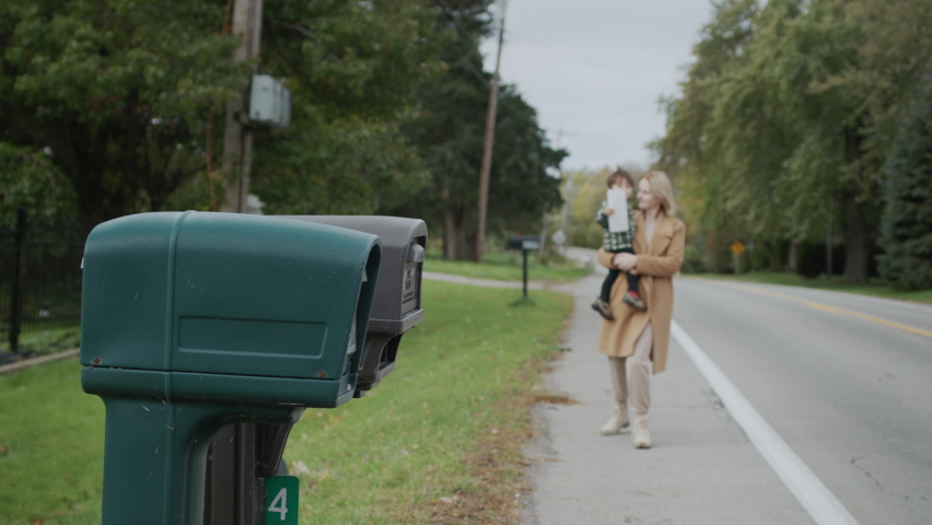 A woman with a child goes to the mailbox to send a letter.