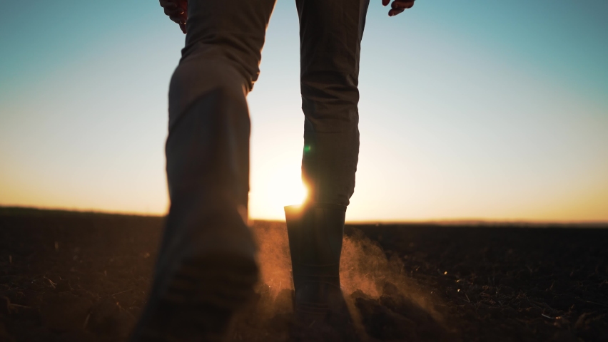 Agriculture. farmer at sunset walk on fertile soil. Farm worker silhouette. The foot of a man in rubber boots walk through the mud. Farmer agronomist works on land plot at sunset. Agriculture concept Royalty-Free Stock Footage #1096349613