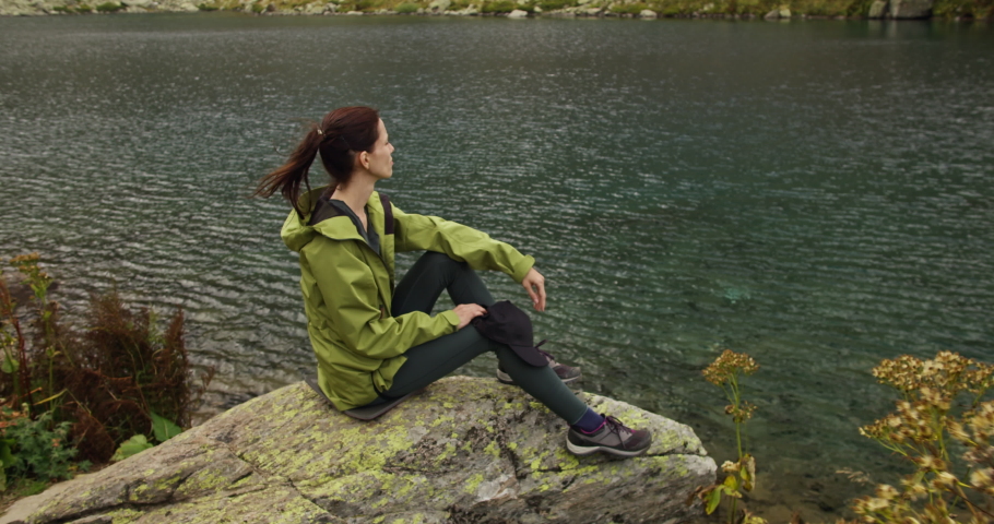 Female traveller looking on glacier mountains lake water, hike in mountain