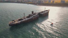 Drone footage of a rusty shipwreck at the Black Sea located next to Costinesti beach, in Romania. Aerial video was shot from a drone while flying at high altitude around the shipwreck at sunset.