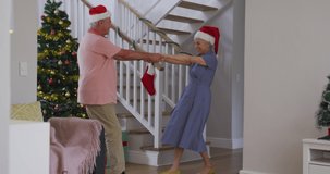 Animation of snow falling over senior caucasian couple wearing santa hats and dancing. Christmas, tradition and celebration concept digitally generated video.