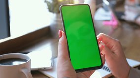 View from shoulder of caucasian woman doing swipe up gesture on chroma key of modern smartphone. Female relaxing in a Chinese restaurant and using cell phone.