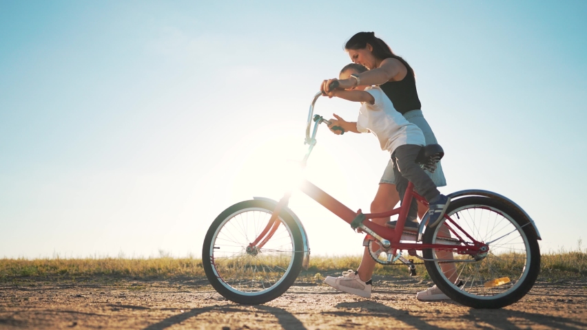 Happy family. Mom teaches her son to ride bike in park. My son is riding a bike for the first time. The child dreams of traveling by bike. The boy is learning to ride a bike. Mom helping hand to son. Royalty-Free Stock Footage #1096372211