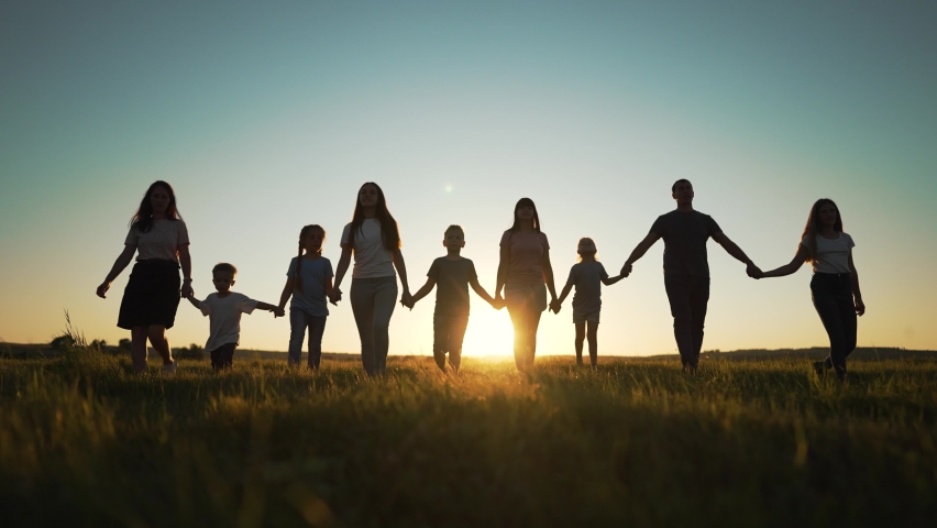 Happy family. Silhouette of large group of people at picnic in park. The family generation walks on the green grass. Parents and children play in nature. Family walking together across field at sunset Royalty-Free Stock Footage #1096372377