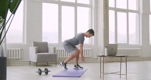 Athletic fitness coach in sportswear showing how to train at home while providing online lesson via laptop