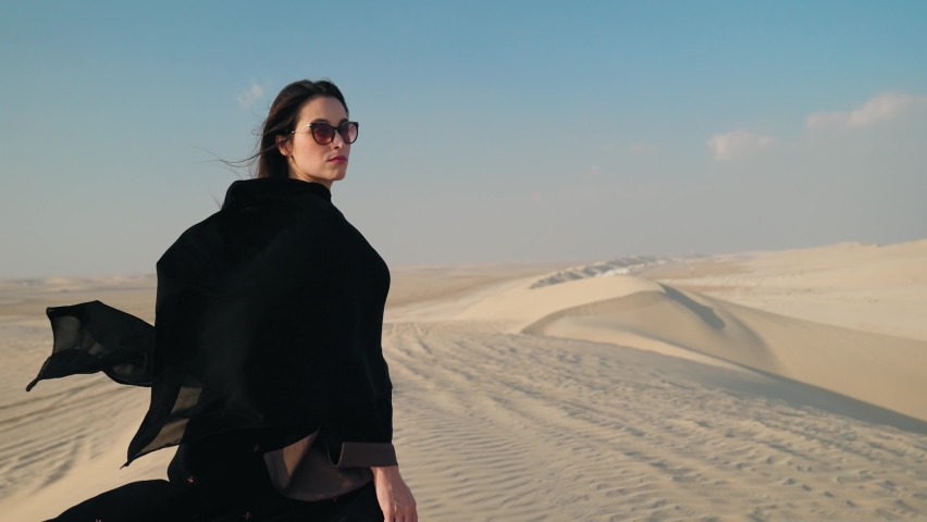 Portrait of beautiful young Arab muslim woman in traditional black hijab. At Doha Qatar. Close up of female wearing sunglasses. Arabian headscarf. Outdoor.
