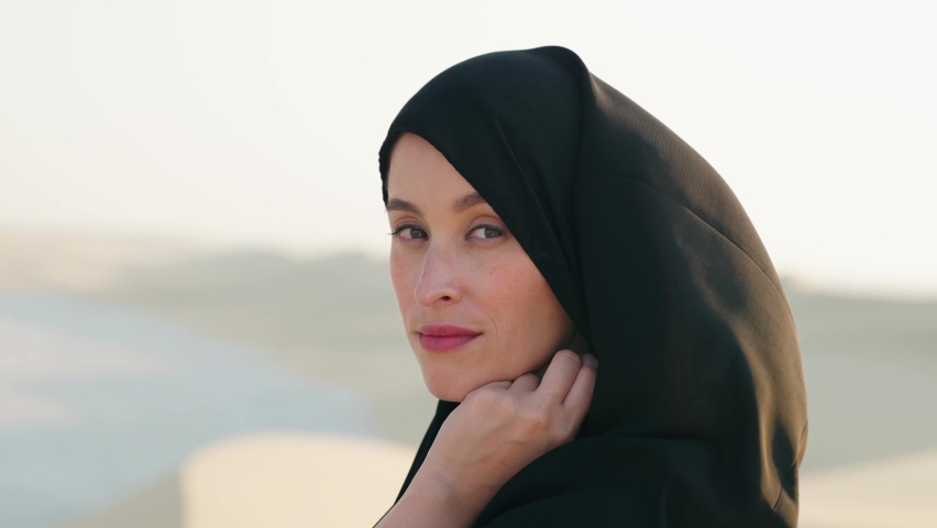 Portrait of beautiful young Arab muslim woman in traditional black hijab. At Doha Qatar. Close up of female joyful face. Arabian headscarf. Outdoor.
