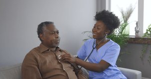 4K video footage of a A young female nurse doctor holds a stethoscope and examines an older mature man from the 60s, a patient, checks the heartbeat at home examination, a medical visit to a home 
