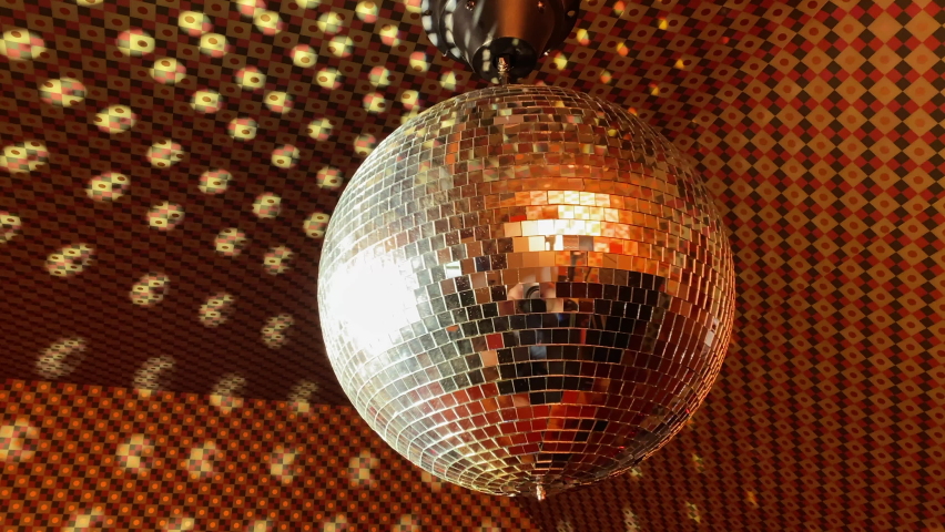 Large disco ball rotates and reflects light in funky 70's style room, close up. Royalty-Free Stock Footage #1096380851