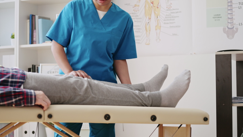 Female doctor helping patient to stretch his leg, post-operative rehabilitation Royalty-Free Stock Footage #1096381875