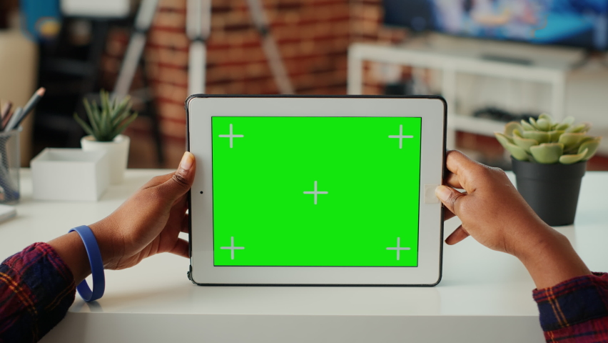 Young entrepreneur using horizontal greenscreen on wireless gadget at home, looking at diplay with isolated template and chroma key background. Working with mockup copyspace. Close up.