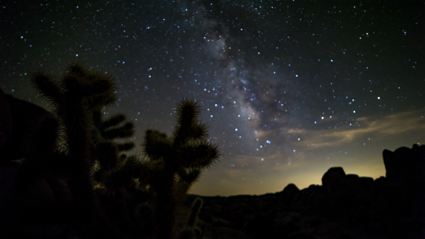 Time Lapse Panning Shot Of Silhouette Glowing Stars Moving Over Rocks At Joshua Tree National Park During Night