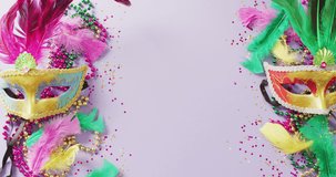 Video of carnival masquerade masks, feathers, confetti and mardi gras beads, with central copy space. Carnival, dressing up, party props, fun and celebration concept.