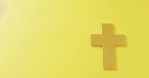 Video of brown christian crucifix cross symbol on yellow background with copy space. Christianity, religion, tradition and celebration concept.