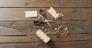 Video of scissors, twine string, buttons and gift tags on dark wood boards with copy space. Creativity, crafts and hobbies concept.