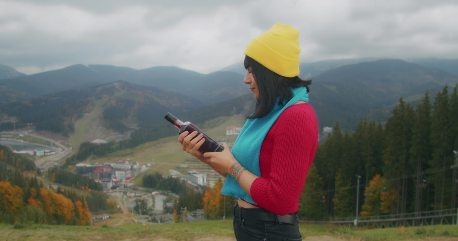 young woman traveler in the mountains warms up with a hot drink. autumn adventures. Generation Z travel