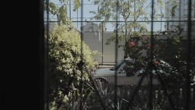 Through a window with a metal grille, you can see a classic vintage car parked on the street. A cinematic shot of an old car from the window of a house. High quality 4k footage