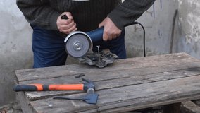 The video shows how a worker holds a grinder in his hands, which cuts metal. Sparks are visible.