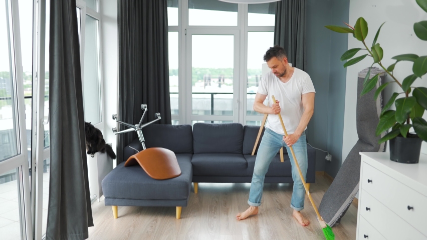 Man cleaning the house and having fun dancing and singing with a broom. Royalty-Free Stock Footage #1096412317