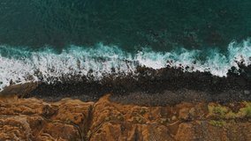 Aerial drone top down view of coastal cliffs and rocky beach in twilight, sunset. Blue ocean water. Amazing sea waves foam crashing on the volcanic stones, rock. Seascape. Tenerife. Canary Island. - Powered by Shutterstock - Get 15% off with code: PIKWIZARD15