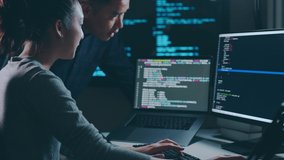 Young Asian woman, developer programmer, software engineer, IT support, with colleague working hard at night overtime on computer to check coding in bugging system together - Powered by Shutterstock - Get 15% off with code: PIKWIZARD15