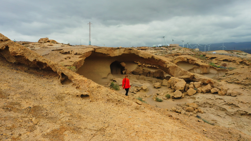 Tourist descending on lava field. Alone girl walks on frozen lava. Natural hole in volcanic rock. Tourist attraction. Arco de Tajao. Limestone arch.
