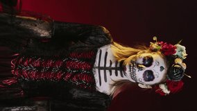 Vertical video: Creepy dead woman trying to lure with hand, reach and tempt victims in studio. Flirty la cavalera catrina model with mexican festival costume on holiday celebration, day of the dead.