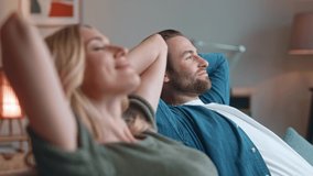 Cute man and pretty woman sitting and relaxing on sofa at home. Beautiful couple husband and wife lying on couch in living room having good time. Carefree relaxed lovely couple. Couple concept. - Powered by Shutterstock - Get 15% off with code: PIKWIZARD15