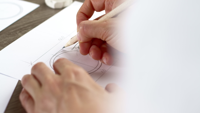 The artist draws a sketch on paper and designs eyeglasses.