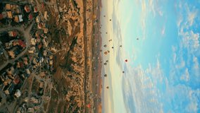 gorgeous aerial vertical shot of dozens of colorful air balloons flying over Cappadocia's rocky landscape. High quality 4k footage