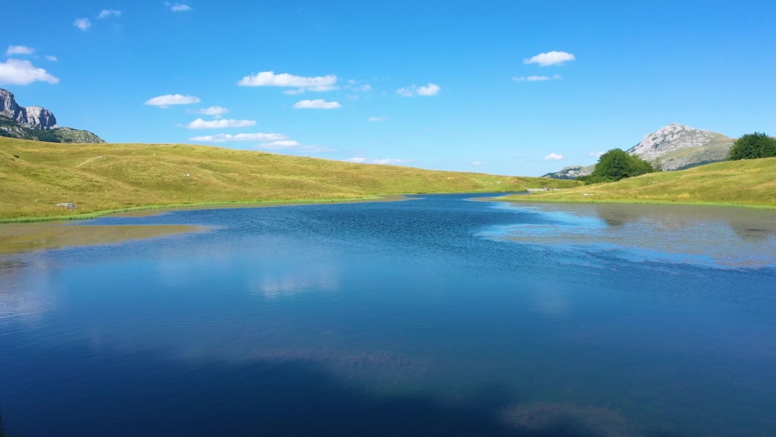 Beautiful landscape with blue water lake and meadow surrounding it on the mountain