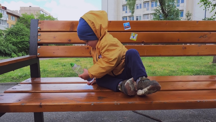 A little boy climbs down from a bench in the park. Copy space - the concept of the problem of safety of children without parental supervision, injuries while playing, hitting, children
