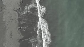 Top view of a sandy beach, sea waves crashing on the shore, sea foam. D-log profile, log video