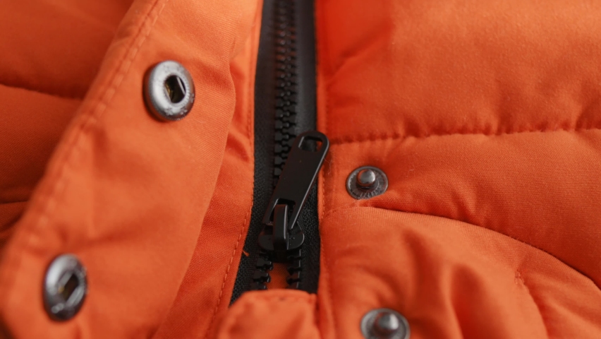 Close-up of female hands open black lock on winter orange jacket, down jacket. Opening closing zipper on clothes. Details of an autumn waterproof jacket. Textile, material, Fashion, Style Royalty-Free Stock Footage #1096447927
