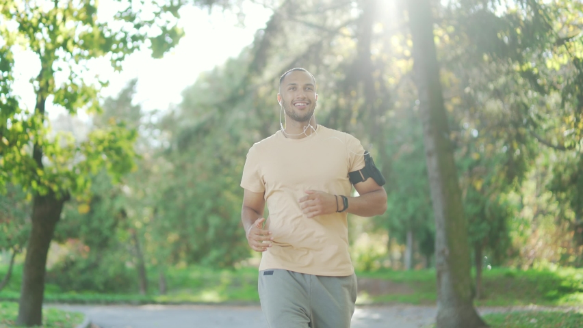 young handsome sporty guy runner, morning run in the city urban park Running outdoors healthy active sport lifestyle. fitness man jogging. listens to music or a podcast in headphones Royalty-Free Stock Footage #1096449205