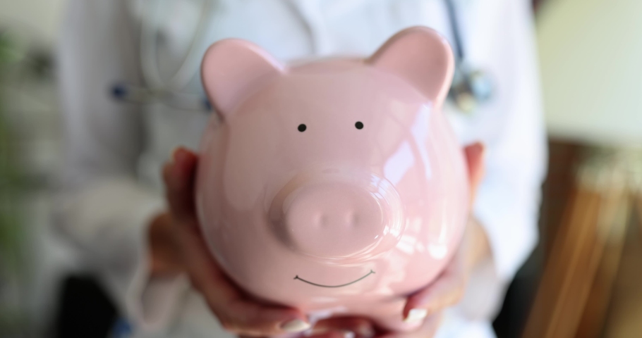A doctor with a pink piggy bank in his hands, a close-up Royalty-Free Stock Footage #1096454975