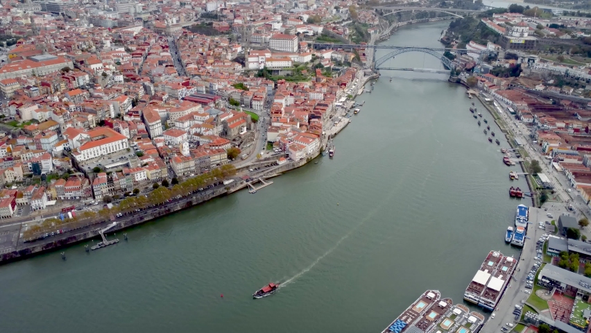 Porto - Portugal, cinematic aerial perspective of city center and River Douro. The second largest city of Portugal and an important travel destination. Boats on river. Cloudy sky. Drone tilt down Royalty-Free Stock Footage #1096455031