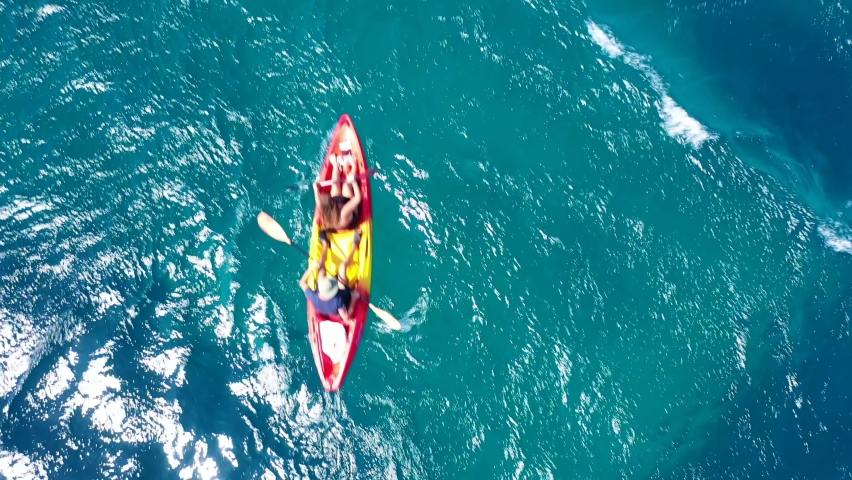 Aerial drone video of couple enjoying sport kayak in tropical exotic resort with crystal clear emerald sea