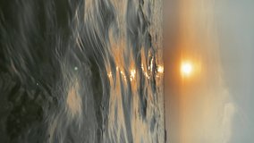 Vertical video. Sunset on the horizon of the Baltic Sea with small waves and birds flying on it