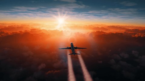 Cinematic view of a commercial airplane making a flight above clouds making a contrail at sunset. Cargo aircraft traveling above orange clouds making a smoke out of engines. Video de stock